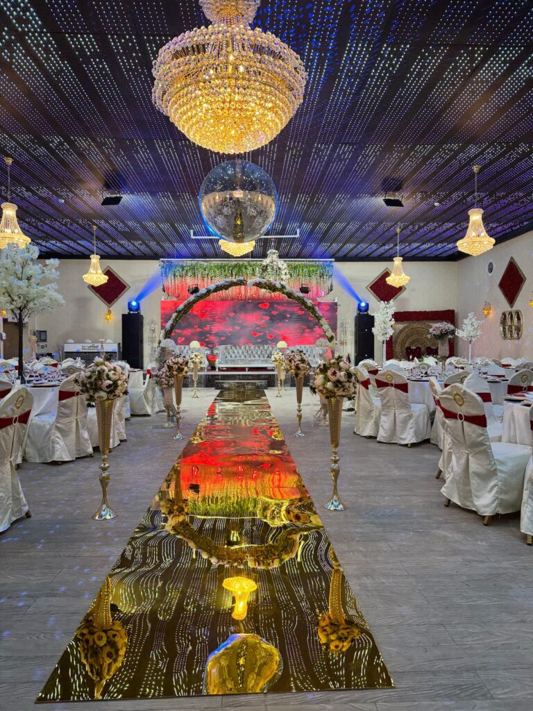 Lavishly decorated wedding hall at Baab-e-Salaam with chandeliers, floral aisle, and stage setup