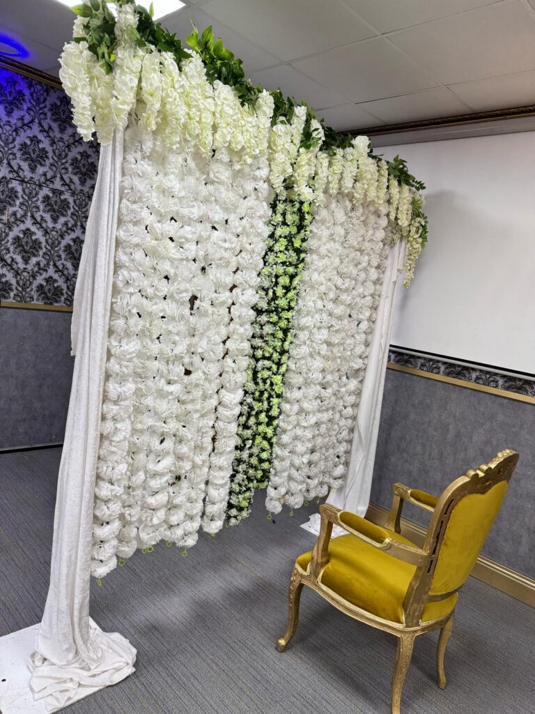 Floral photo booth backdrop with golden chair at Baab-e-Salaam event hall
